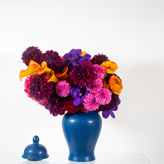 Blue vase with a colorful bouquet of flowers on a white background